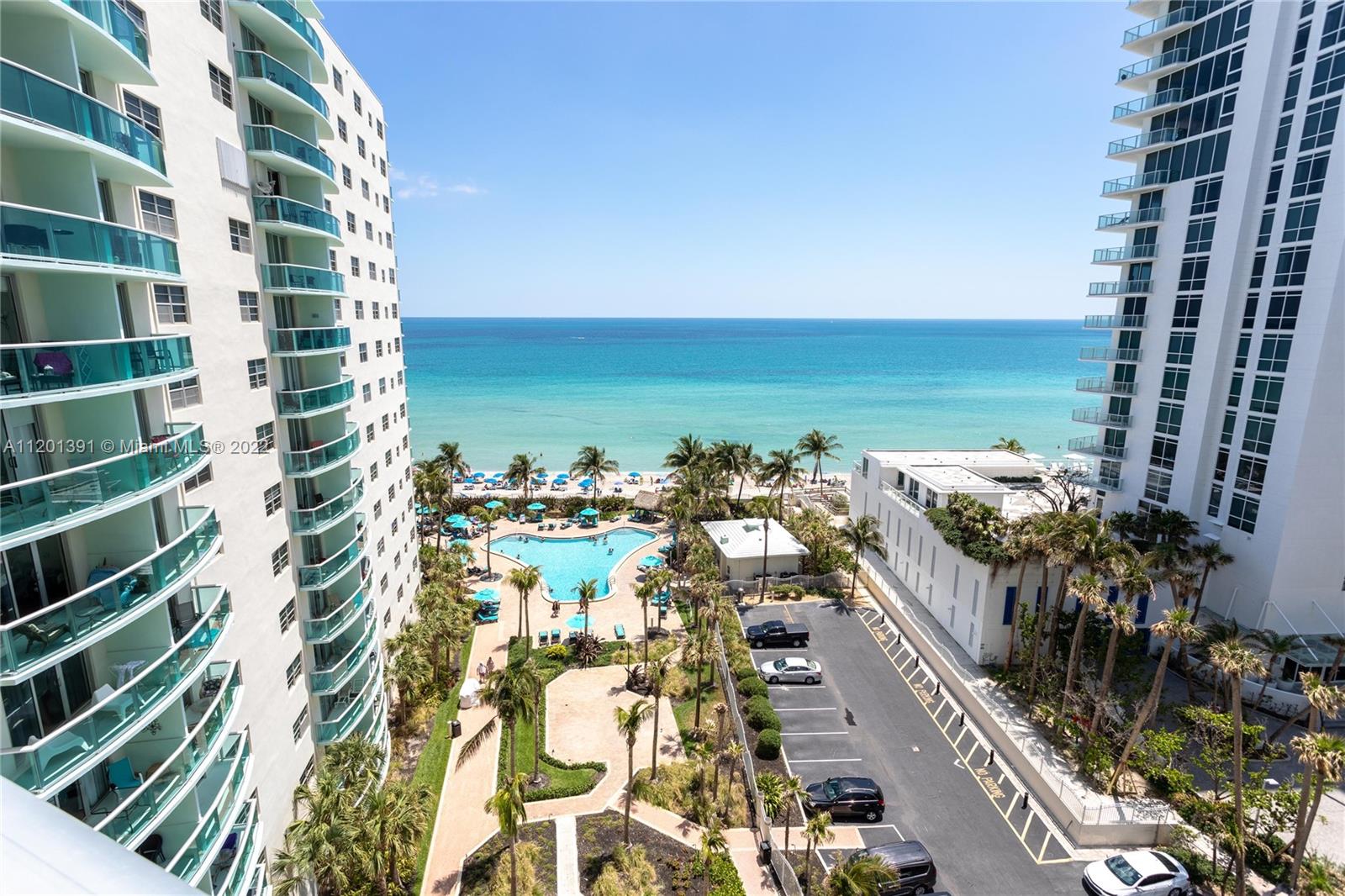 An elevated view shows two high-rise buildings flanking a swimming pool, parking lot, and beach — 3901 S Ocean Dr # 10M, Hollywood FL 33019, HOLLYWOOD, FL