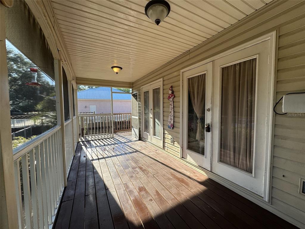 A single-story house with light yellow siding, a screened front porch, and a wooden deck — 38932 CENTRAL AVENUE, ZEPHYRHILLS, FL
