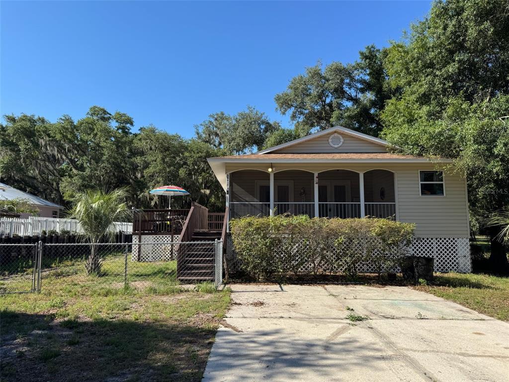 A screened-in porch features a wooden deck, white railings, and two ceiling lights — 38932 CENTRAL AVENUE, ZEPHYRHILLS, FL