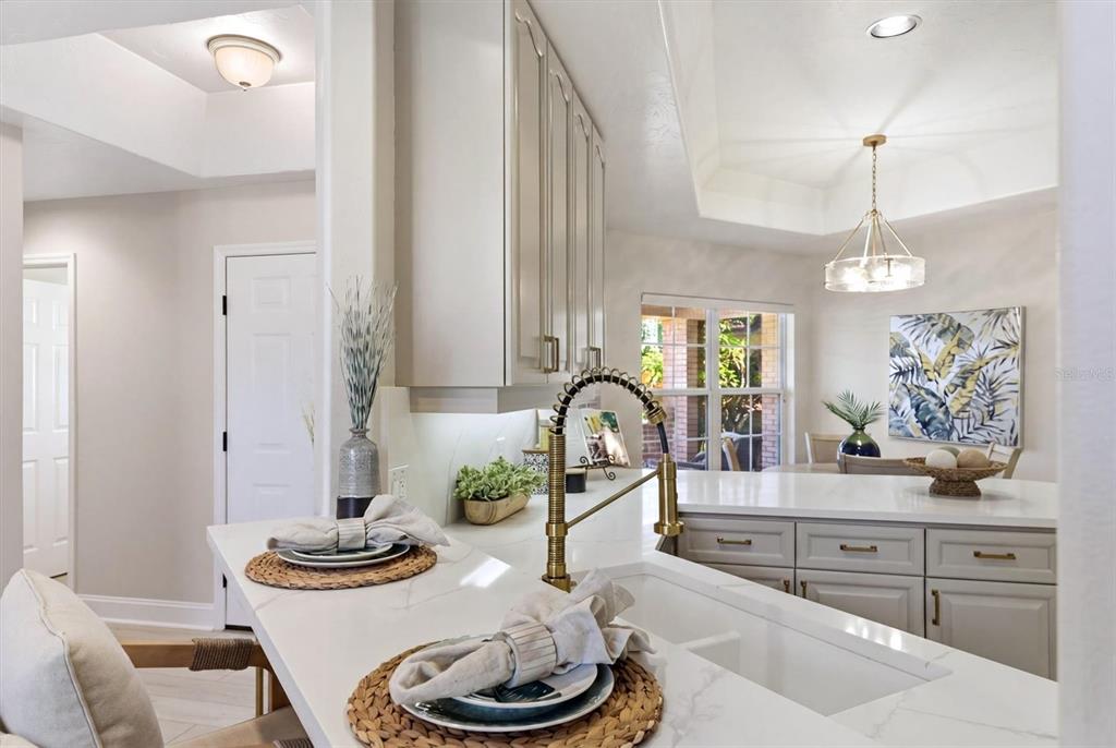 A kitchen features white countertops, light gray cabinets, a brass faucet, and a dining area — 1703 STARLING DRIVE UNIT 1703, SARASOTA, FL