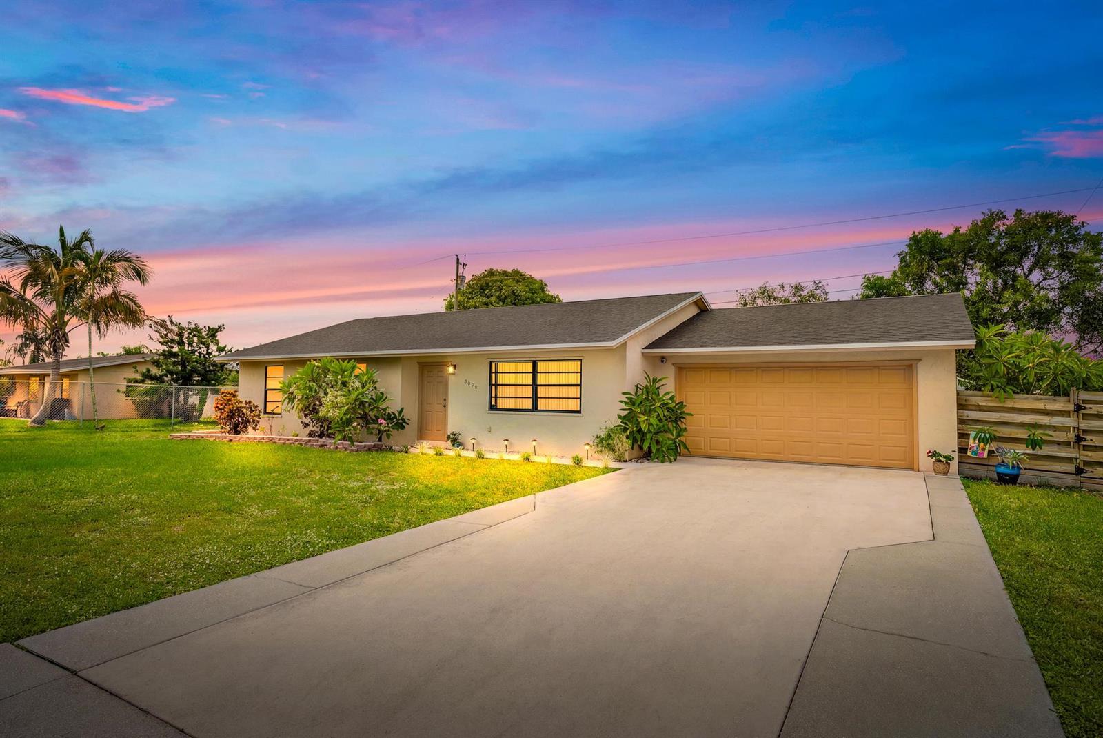 A single-story house with a tan exterior, a two-car garage, and a concrete driveway — 9090 Palladium Place, Lake Worth FL 33467, LAKE WORTH, FL