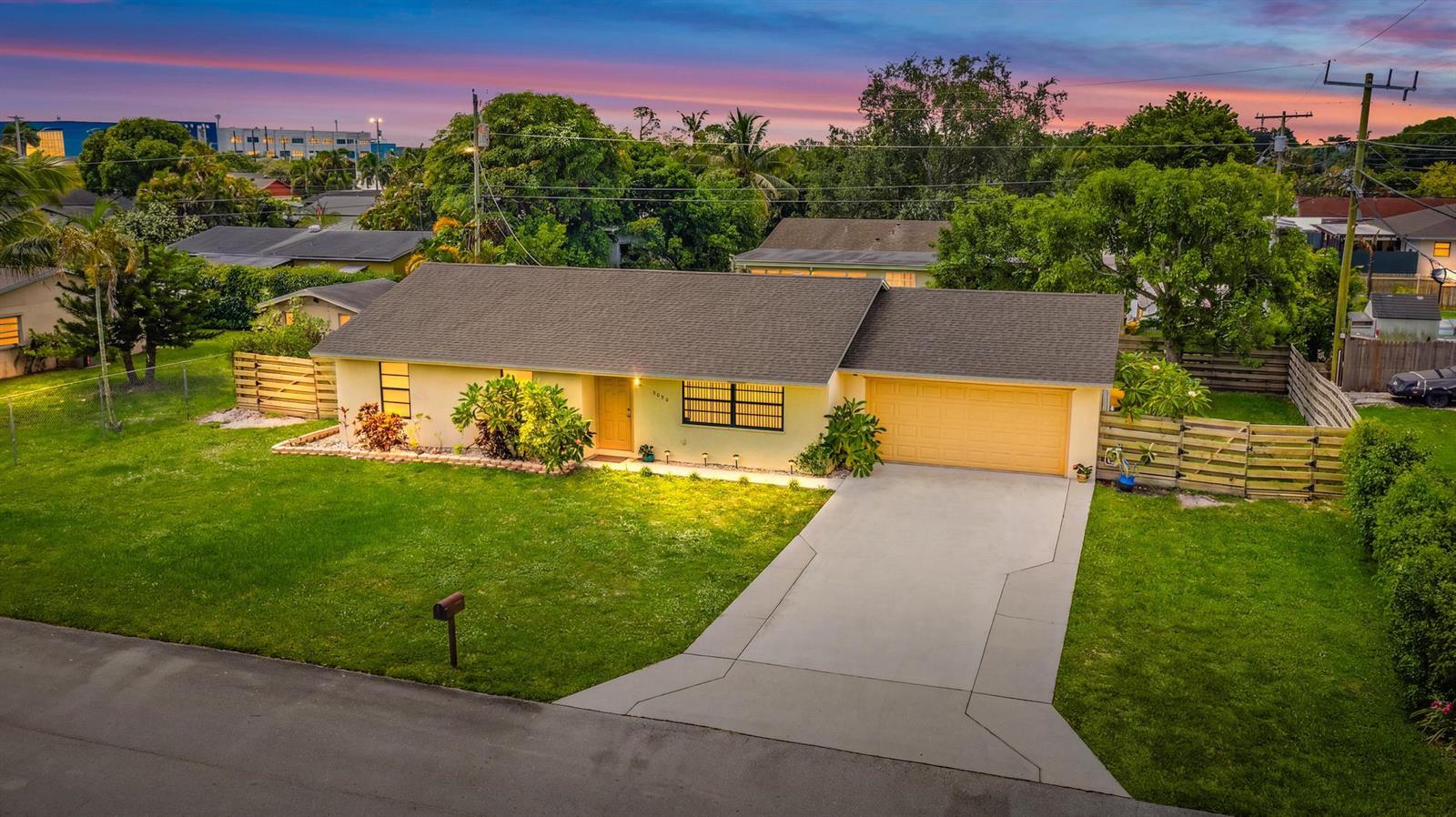 An aerial view of a single-story yellow house with a driveway and a grassy lawn — 9090 Palladium Place, Lake Worth FL 33467, LAKE WORTH, FL