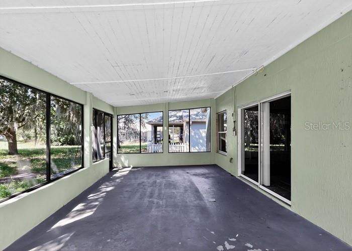 An enclosed porch with a painted concrete floor, large windows, and light green walls — 2016 NEWTOWN ROAD, GROVELAND, FL
