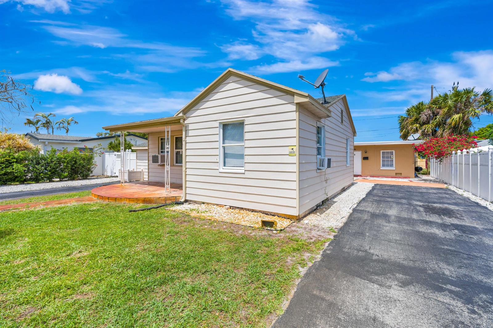 A gravel courtyard sits between a tan stucco building and a light-colored siding structure — 505 Foresteria Drive, Lake Park FL 33403, LAKE PARK, FL