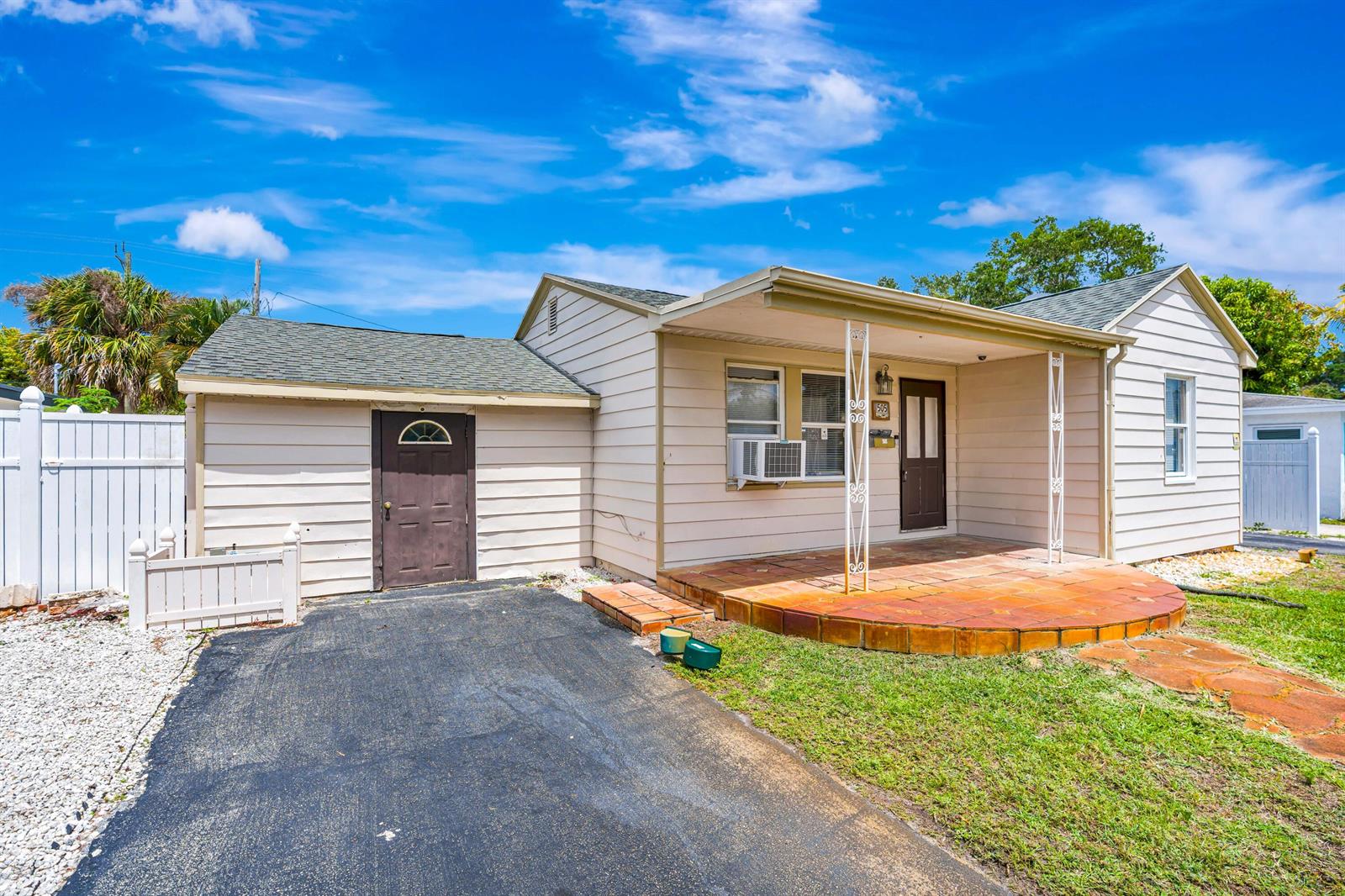 A single-story house with light siding, a gravel yard, and a paved driveway — 505 Foresteria Drive, Lake Park FL 33403, LAKE PARK, FL