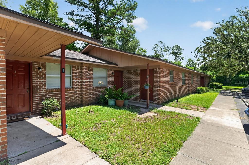A single-story brick apartment building with a sidewalk and a small front lawn — 20420 NW 243RD DRIVE, HIGH SPRINGS, FL