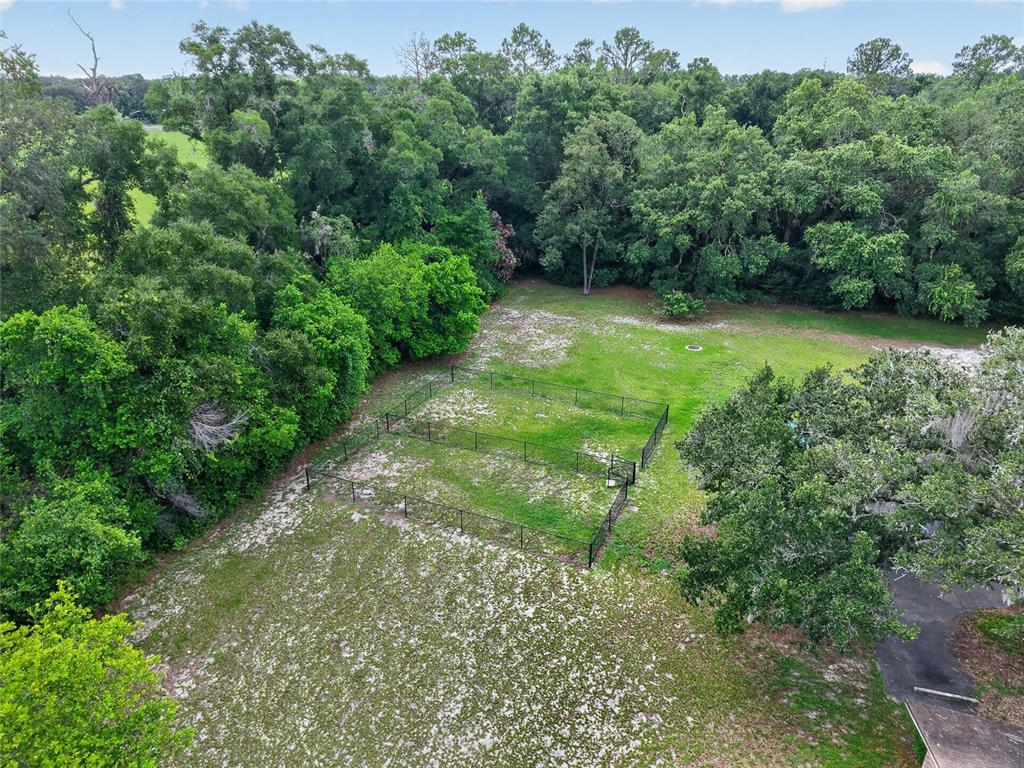 An aerial view shows a fenced-in yard surrounded by dense trees and green lawn — 20420 NW 243RD DRIVE, HIGH SPRINGS, FL