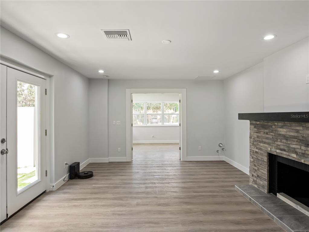 A living room features light-colored walls, wood-look flooring, a stone fireplace, and a glass door — 1190 W LAKESHORE DRIVE, CLERMONT, FL