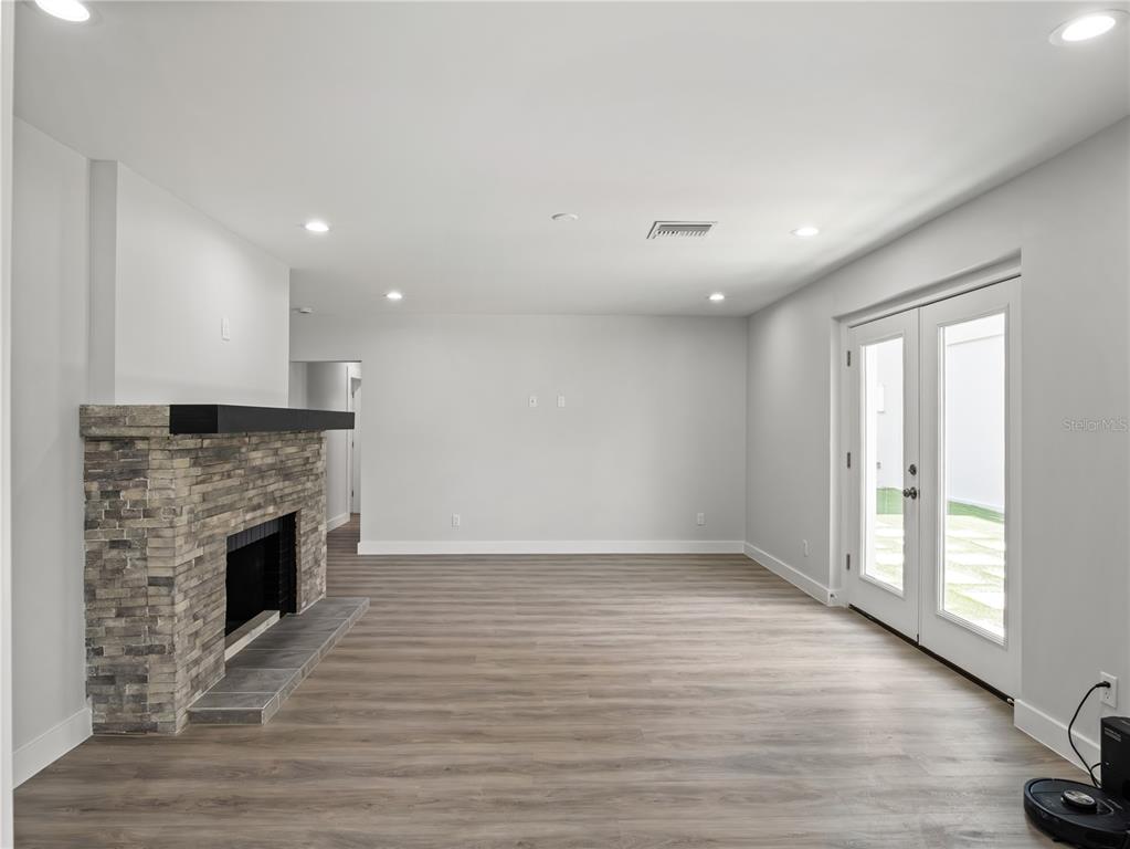 A living room features a stone fireplace, light wood-look flooring, and glass double doors — 1190 W LAKESHORE DRIVE, CLERMONT, FL