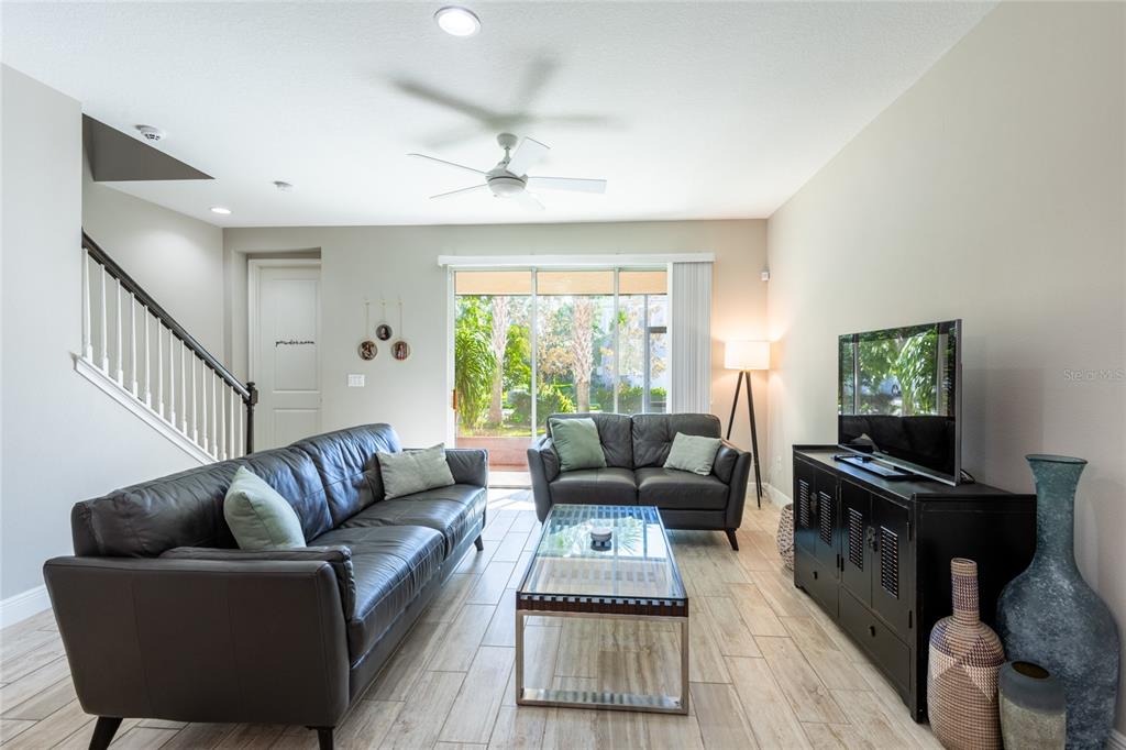 A living room features dark leather sofas, a glass coffee table, and tile flooring — 17847 ALTHEA BLUE PLACE, LUTZ, FL