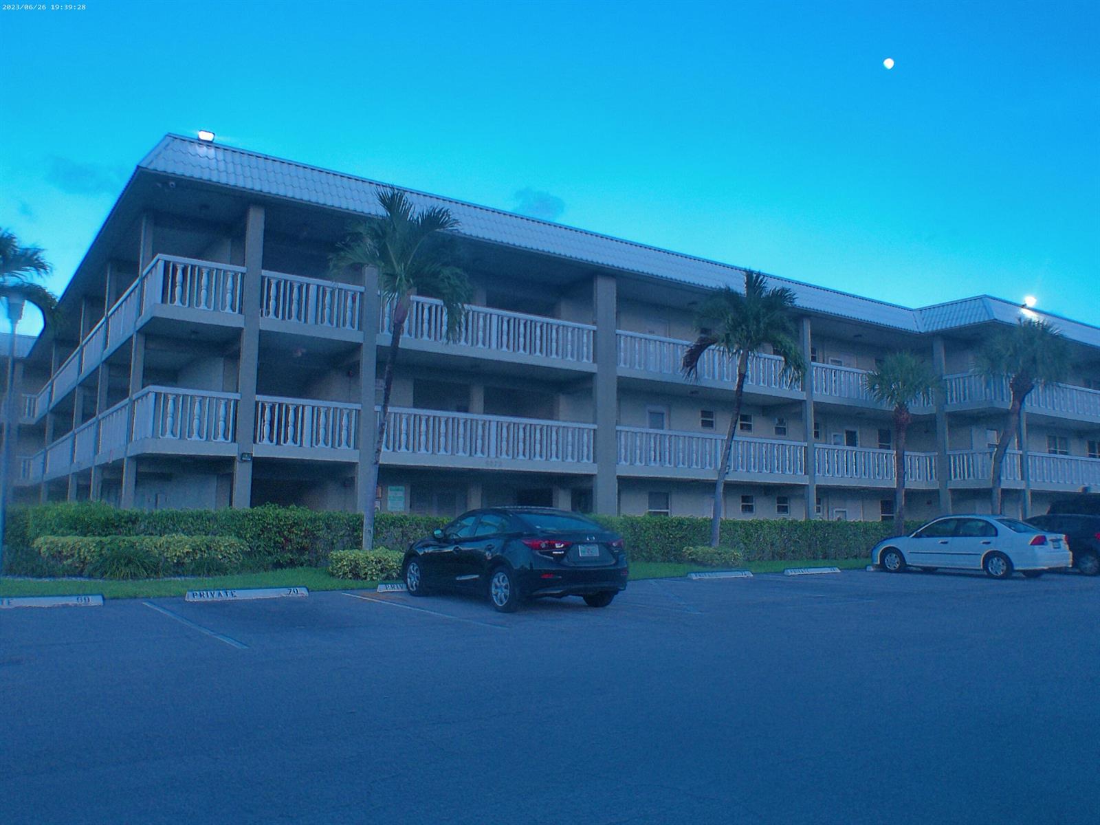 An exterior view of a three-story apartment building with balconies and a parking lot — 9872 Marina Boulevard # 1434, Boca Raton FL 33433, BOCA RATON, FL