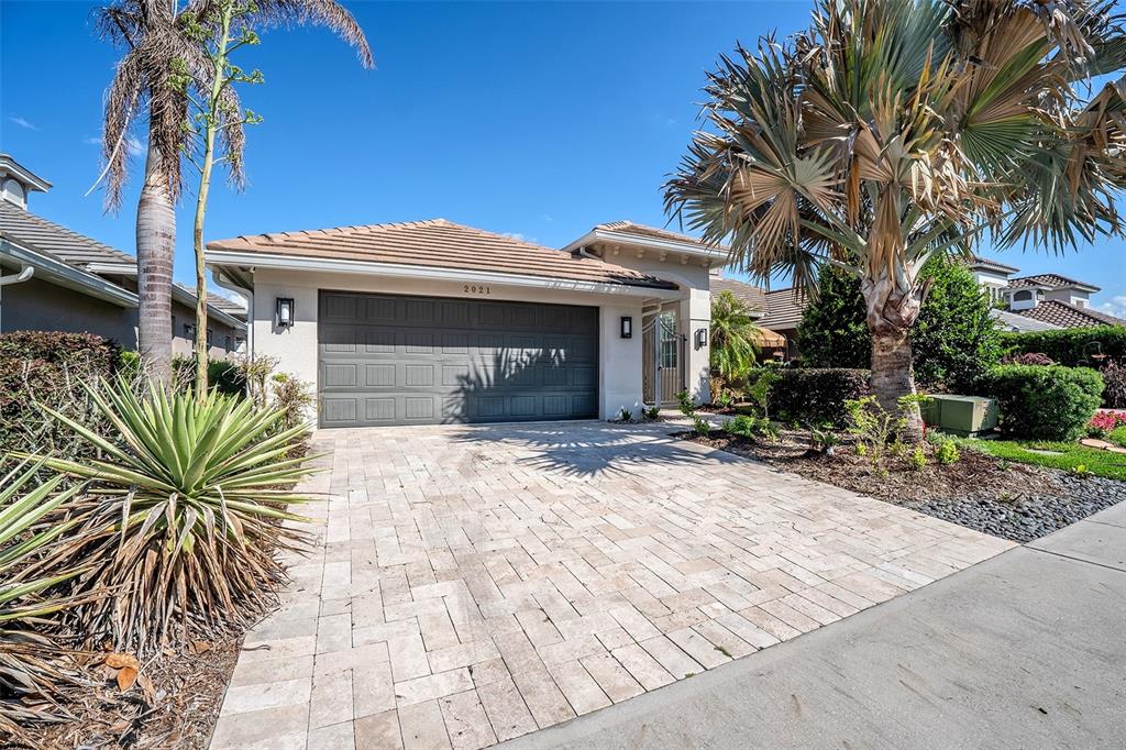 A single-story house with a paved driveway, a two-car garage, and palm trees — 2021 SHERBROOK AVENUE, DAVENPORT, FL