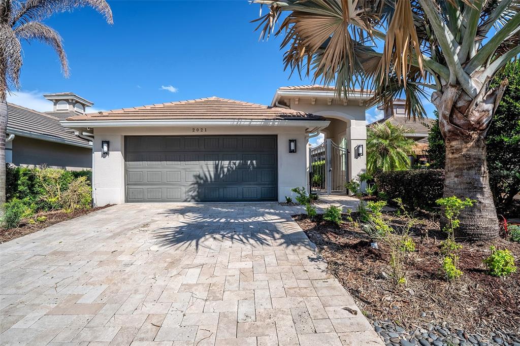 A single-story house exterior with a gray garage door, paved driveway, and palm trees — 2021 SHERBROOK AVENUE, DAVENPORT, FL
