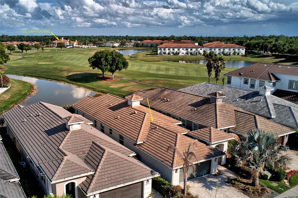 An aerial view shows residential townhomes with tile roofs overlooking a golf course and pond — 2021 SHERBROOK AVENUE, DAVENPORT, FL