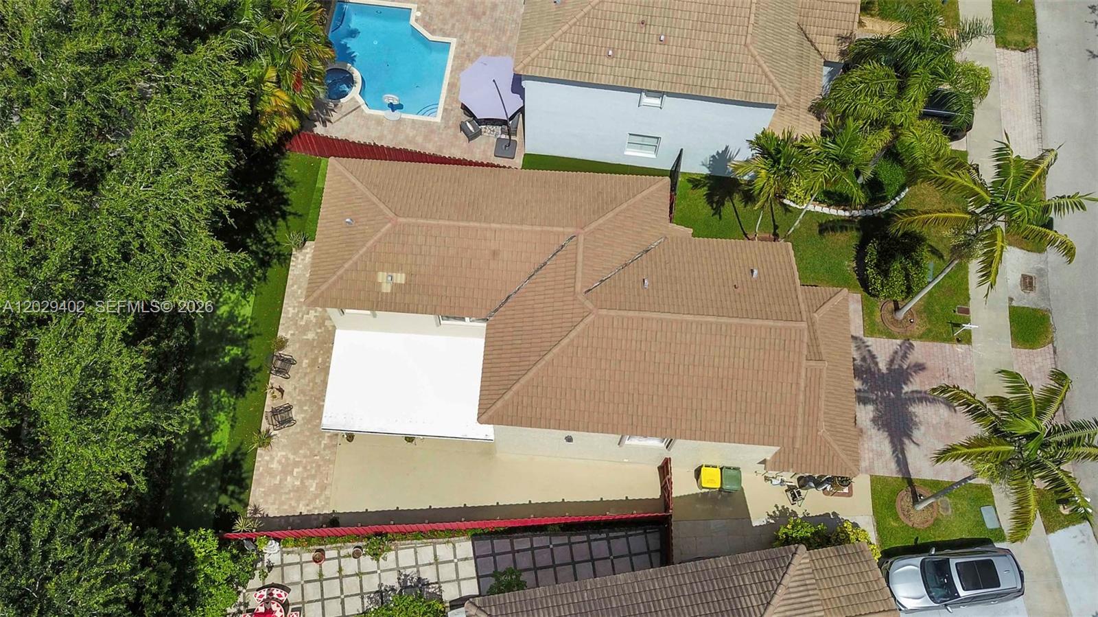 An aerial view shows a house with a tiled roof, a patio, and a pool — HOMESTEAD, FL