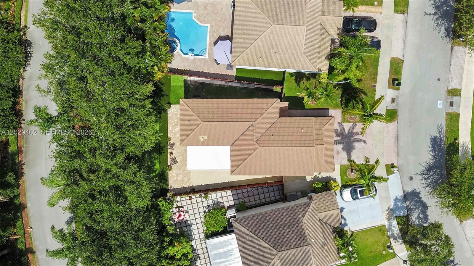 An aerial view shows a residential house with a tiled roof, pool, and driveway — HOMESTEAD, FL