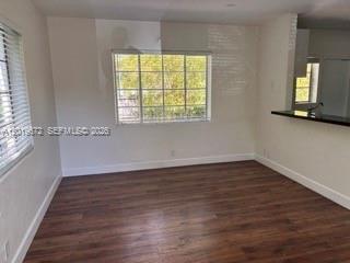 An empty room features dark wood-look flooring, white walls, and a large window — 3132 Elizabeth St # B, Miami FL 33133, MIAMI, FL