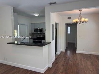 A kitchen with a breakfast bar overlooks a dining area with wood-look flooring and chandelier — 3132 Elizabeth St # B, Miami FL 33133, MIAMI, FL