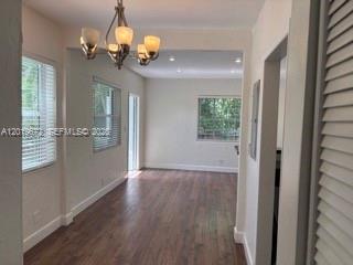 An interior view of a room with wood-look flooring, a chandelier, and multiple windows — 3132 Elizabeth St # B, Miami FL 33133, MIAMI, FL