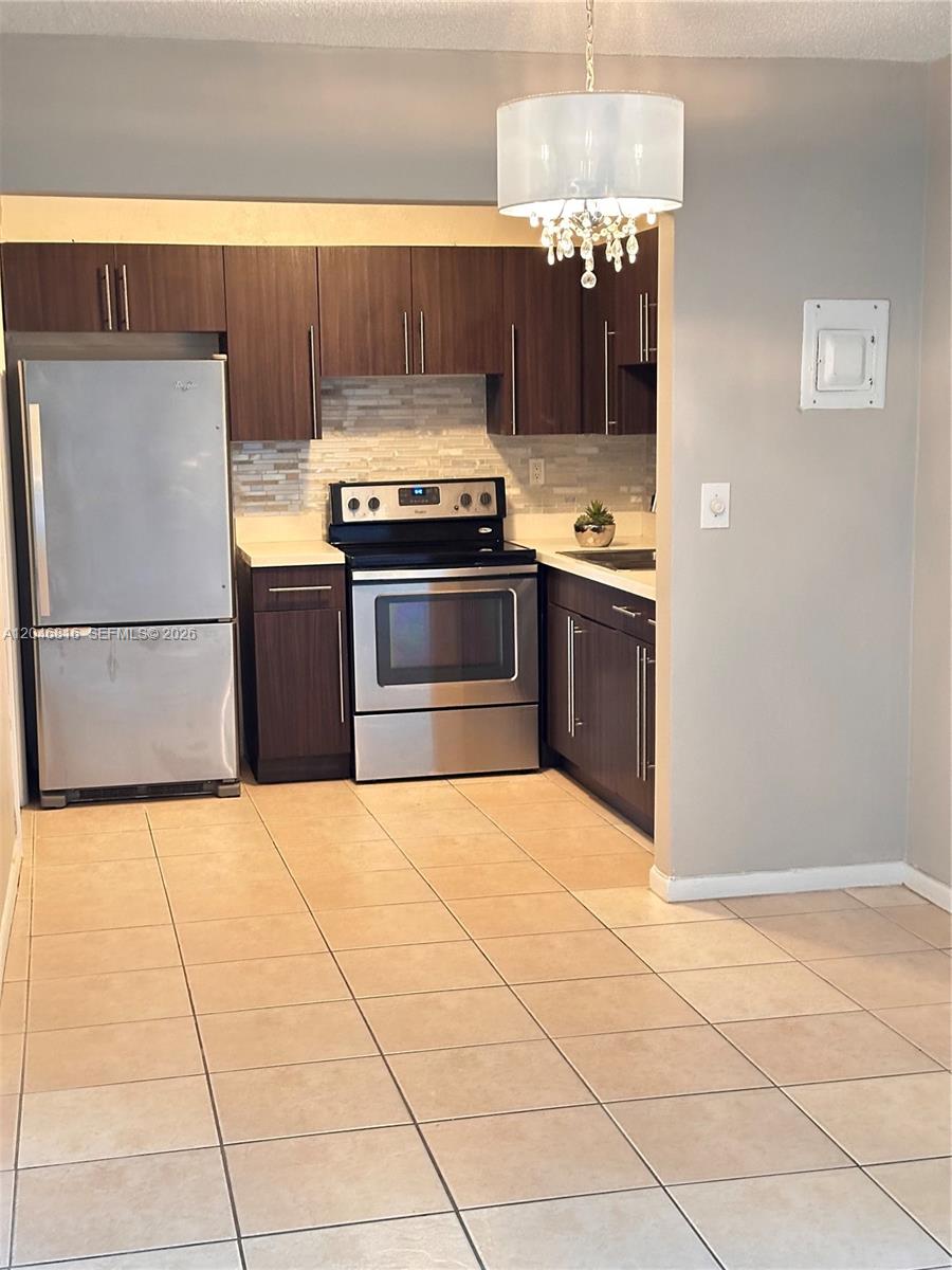 A kitchen features dark wood cabinets, stainless steel appliances, and light-colored tile flooring — 1720 Funston St # 203, Hollywood FL 33020, HOLLYWOOD, FL