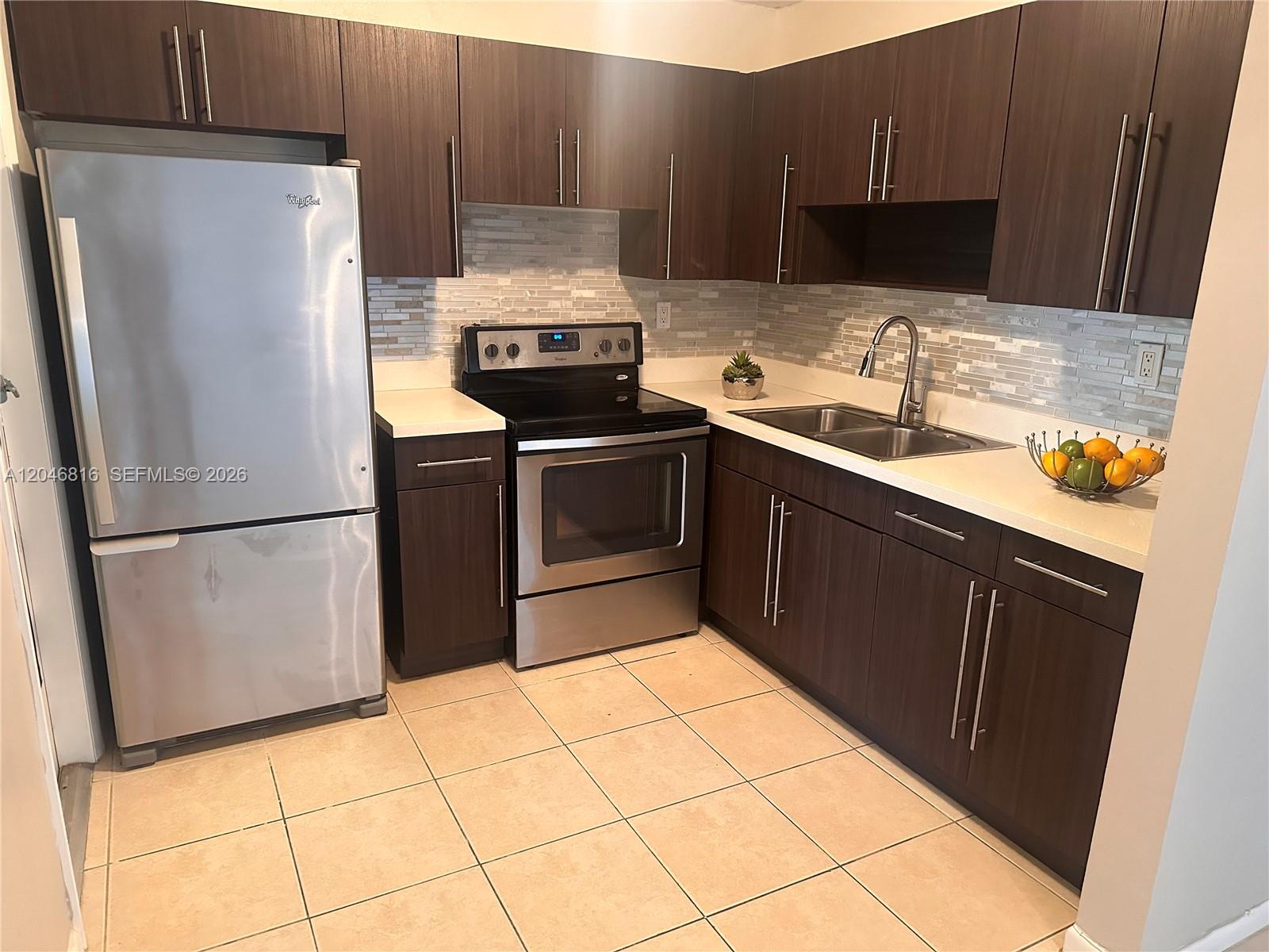 A kitchen features dark wood cabinets, stainless steel appliances, white countertops, and a tiled backsplash — 1720 Funston St # 203, Hollywood FL 33020, HOLLYWOOD, FL