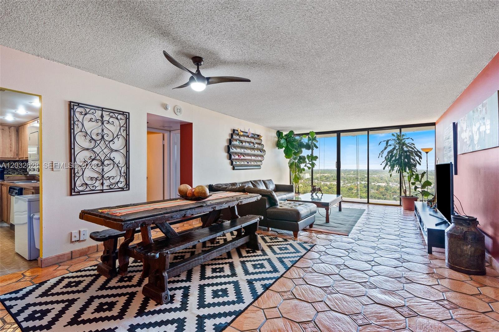 A living and dining area features tile floors, a wooden table, and floor-to-ceiling windows — 780 NE 69th St # 2404, Miami FL 33138, MIAMI, FL