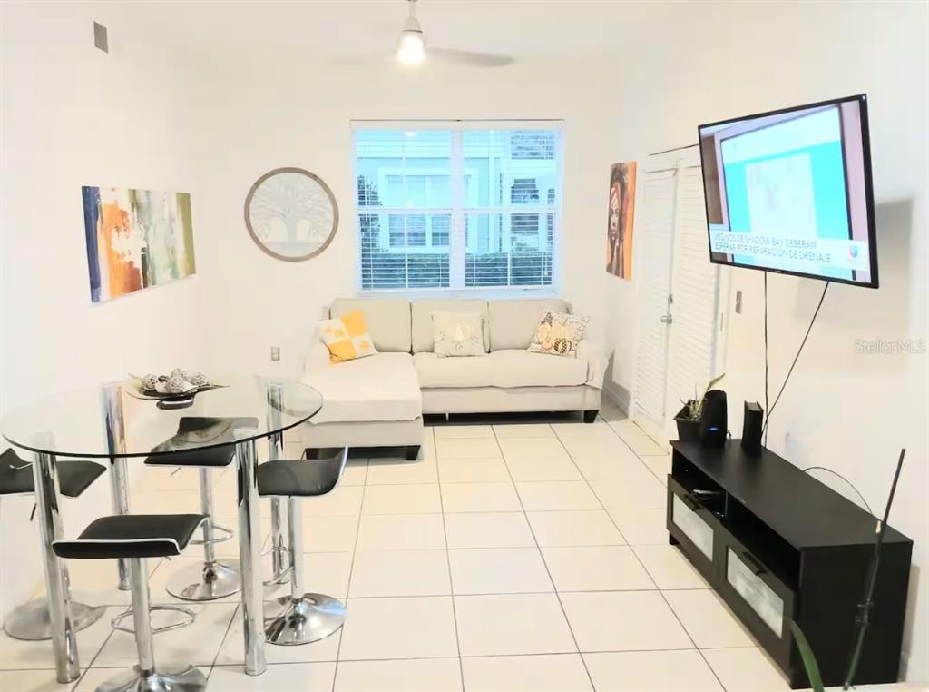 A living room features white tile floors, a glass dining table, and a sectional sofa — 4019 VENETIAN BAY DRIVE UNIT 102, KISSIMMEE, FL