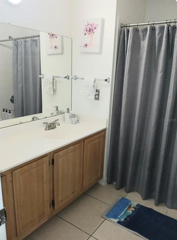 A bathroom features a wooden vanity, a large mirror, and a gray shower curtain — 4019 VENETIAN BAY DRIVE UNIT 102, KISSIMMEE, FL