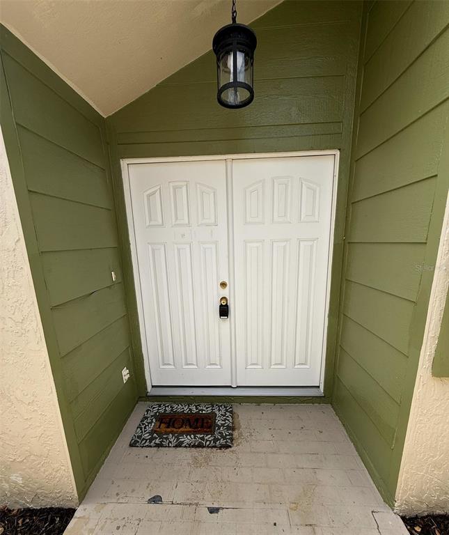 A front entryway features double white doors, a hanging lantern, and a small welcome mat — 12905 SETTLERS DRIVE, HUDSON, FL