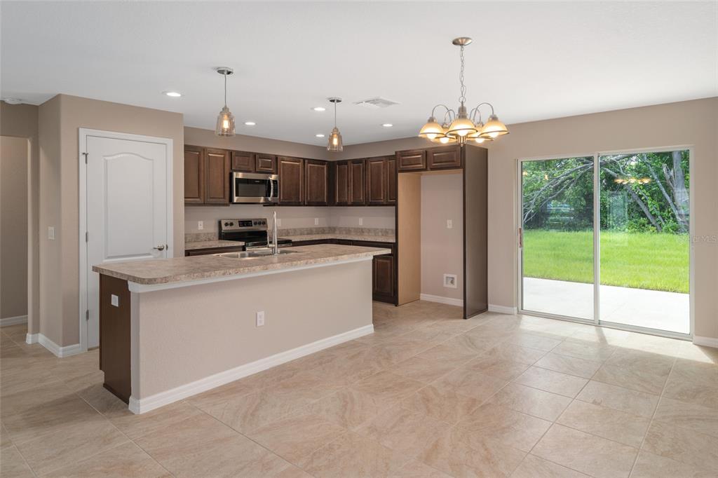 A kitchen features dark wood cabinets, a breakfast bar, tile flooring, and a sliding glass door — 16476 KAKAWI ROAD, BROOKSVILLE, FL