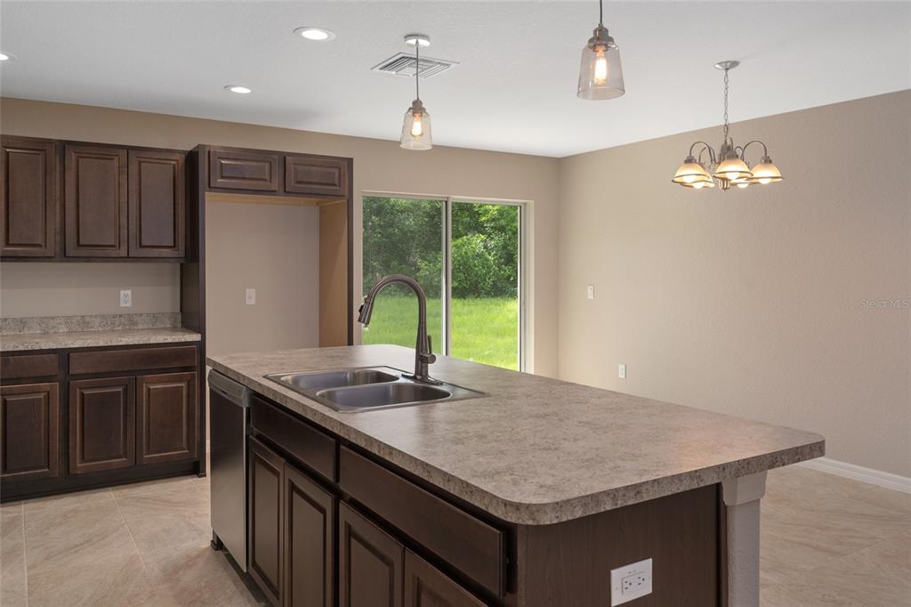 A kitchen with dark wood cabinets, a central island with a sink, and sliding glass doors — 16476 KAKAWI ROAD, BROOKSVILLE, FL