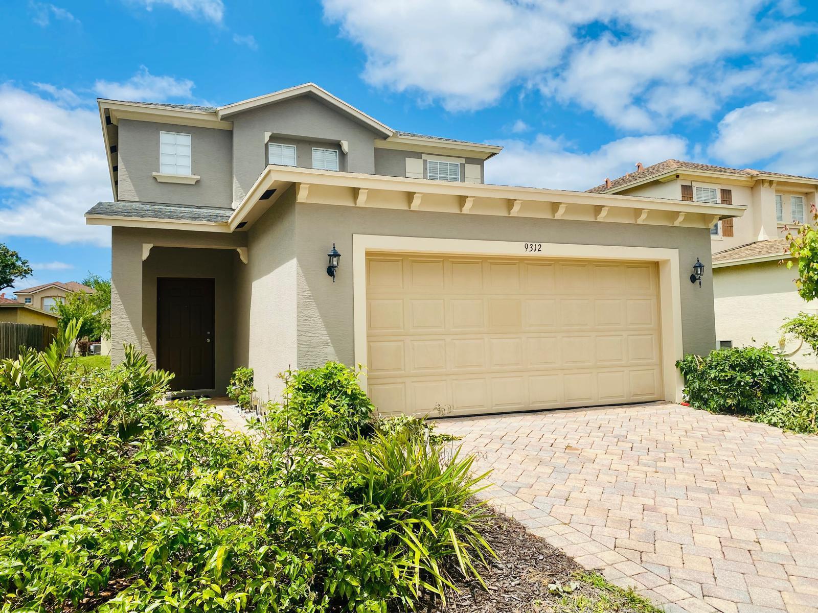 A two-story house with a beige garage door and a brick paver driveway — 9312 Natures Way, Fort Pierce FL 34945, FORT PIERCE, FL