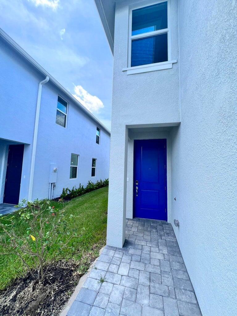 A blue front door is set in a recessed entryway of a light-colored stucco home — 254 Osprey Preserve Boulevard, Jensen Beach FL 34957, JENSEN BEACH, FL