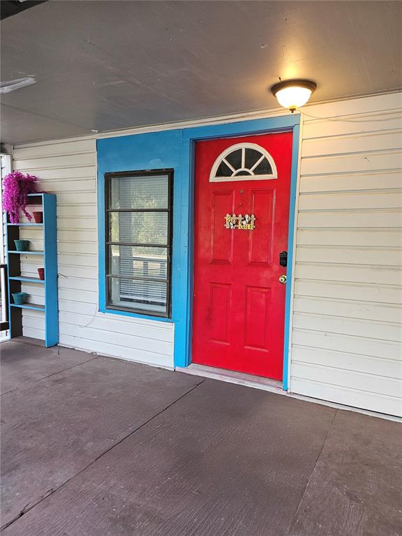 A covered porch features a bright red front door, a blue-trimmed window, and shelving — 10250 SE 108TH TERRACE ROAD, OCALA, FL
