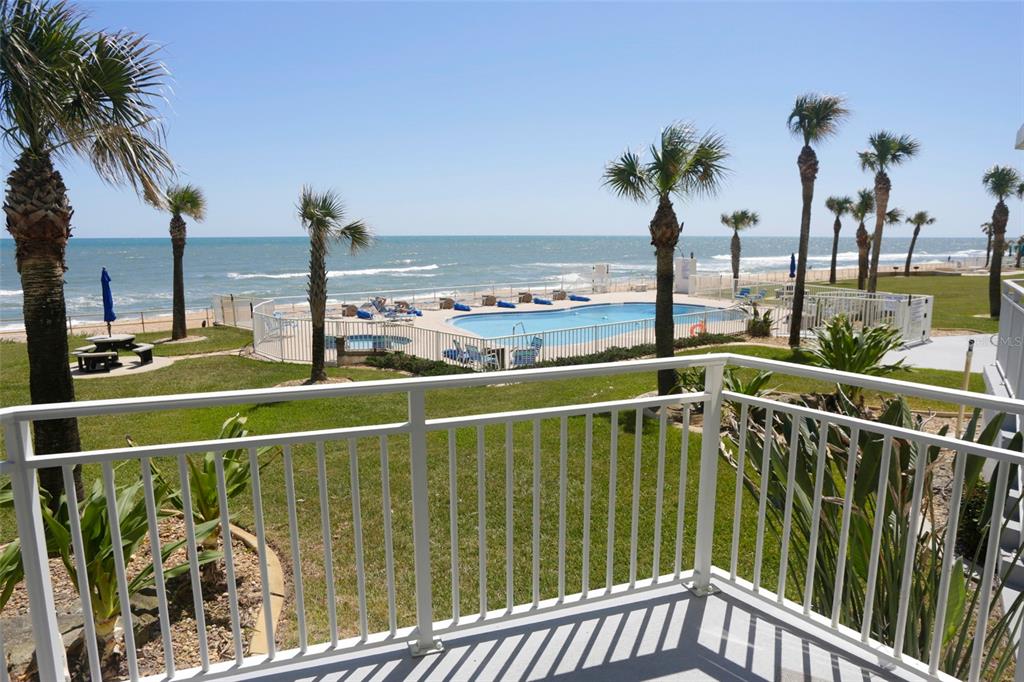 A balcony overlooks a swimming pool, palm trees, and the ocean — 1155 OCEAN SHORE BOULEVARD UNIT 102, ORMOND BEACH, FL