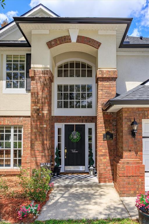 The front exterior of a two-story house features a brick entryway with a black door — 50 OAK BEND COURT, OVIEDO, FL