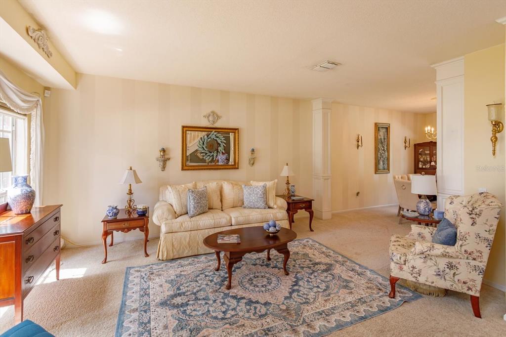 A living room features a beige sofa, floral armchair, coffee table, and striped wallpaper — 50 OAK BEND COURT, OVIEDO, FL