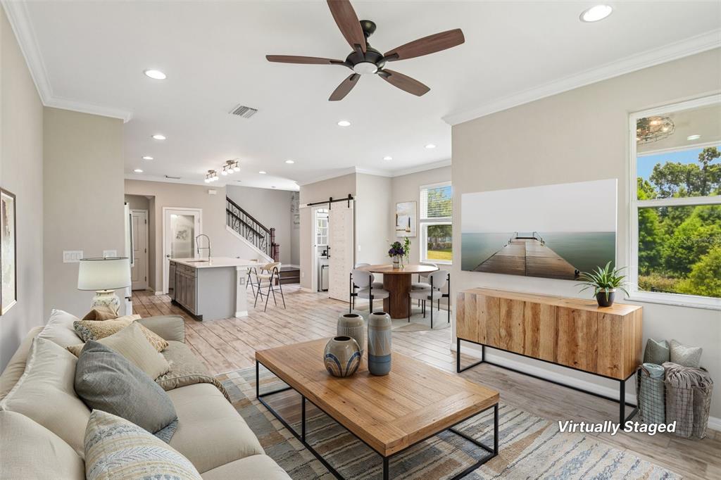 This open-concept living and dining area features wood-look tile flooring and a modern kitchen — 6706 ROCKY PARK STREET, TAMPA, FL