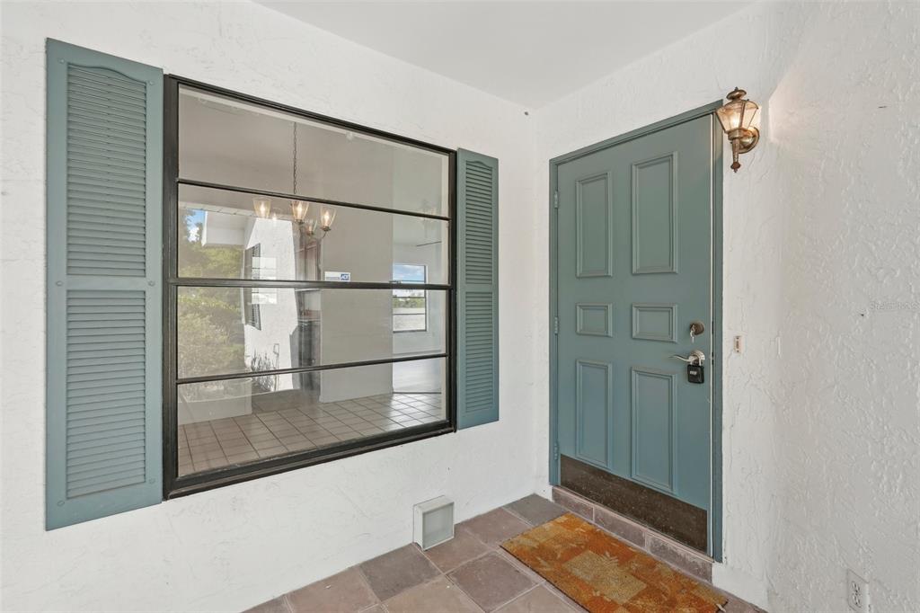 A front entryway features a blue door, a large window with shutters, and tiled flooring — 1613 COMFY COURT, SUN CITY CENTER, FL
