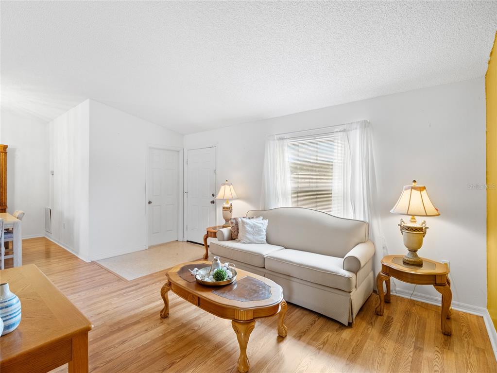 A living room features a beige sofa, wooden coffee table, two lamps, and hardwood flooring — 867 NE FAIRHAVEN, PALM BAY, FL