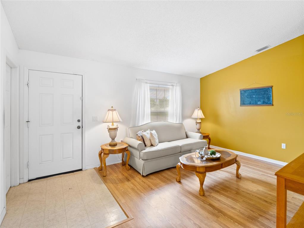 A living room features a beige sofa, two end tables with lamps, and a yellow wall — 867 NE FAIRHAVEN, PALM BAY, FL