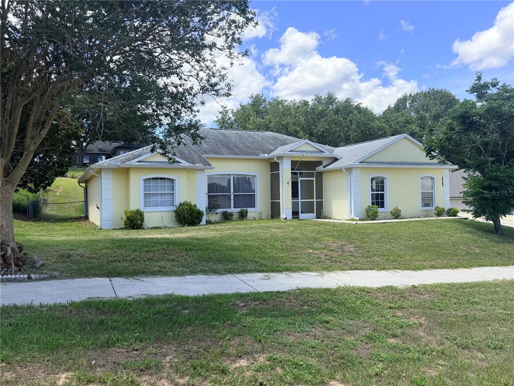 A yellow single-story house with a screened entryway sits on a grassy lot — 1011 SCENIC VIEW CIRCLE, MINNEOLA, FL