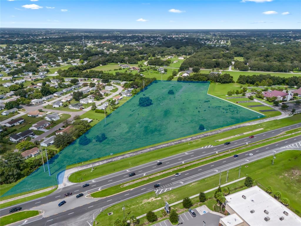 An aerial view shows a large, highlighted vacant lot adjacent to a multi-lane highway — 00 SE US HWY 441, SUMMERFIELD, FL
