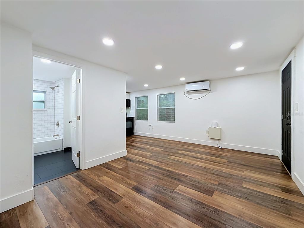 A room with wood-look flooring, recessed lighting, a wall-mounted air conditioner, and an attached bathroom — 800 15TH AVENUE S, ST PETERSBURG, FL