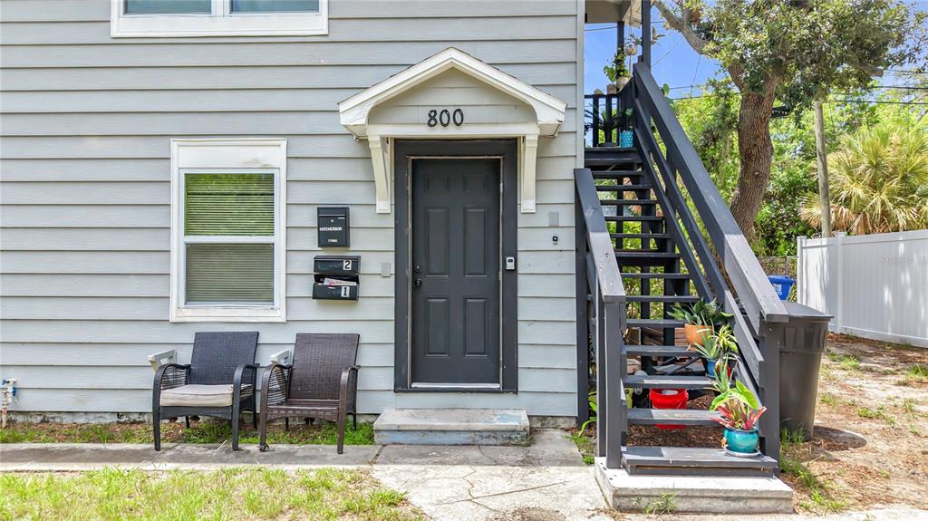 The exterior of a gray house features a dark door, stairs, and two outdoor chairs — 800 15TH AVENUE S, ST PETERSBURG, FL