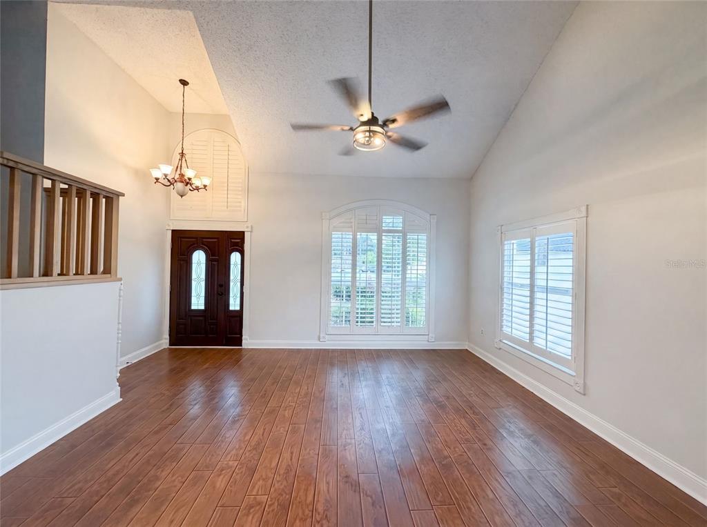A living room features wood flooring, a vaulted ceiling with a fan, and plantation shutters — 1701 LARABIE COURT, BRANDON, FL