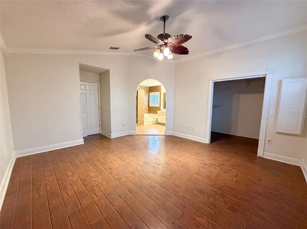 An empty bedroom features wood-look flooring, a ceiling fan, and an arched doorway to a bathroom — 1701 LARABIE COURT, BRANDON, FL