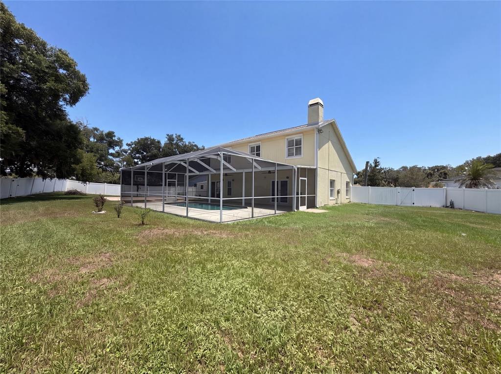 The exterior of a yellow two-story house features a screened-in pool and a fenced yard — 1701 LARABIE COURT, BRANDON, FL