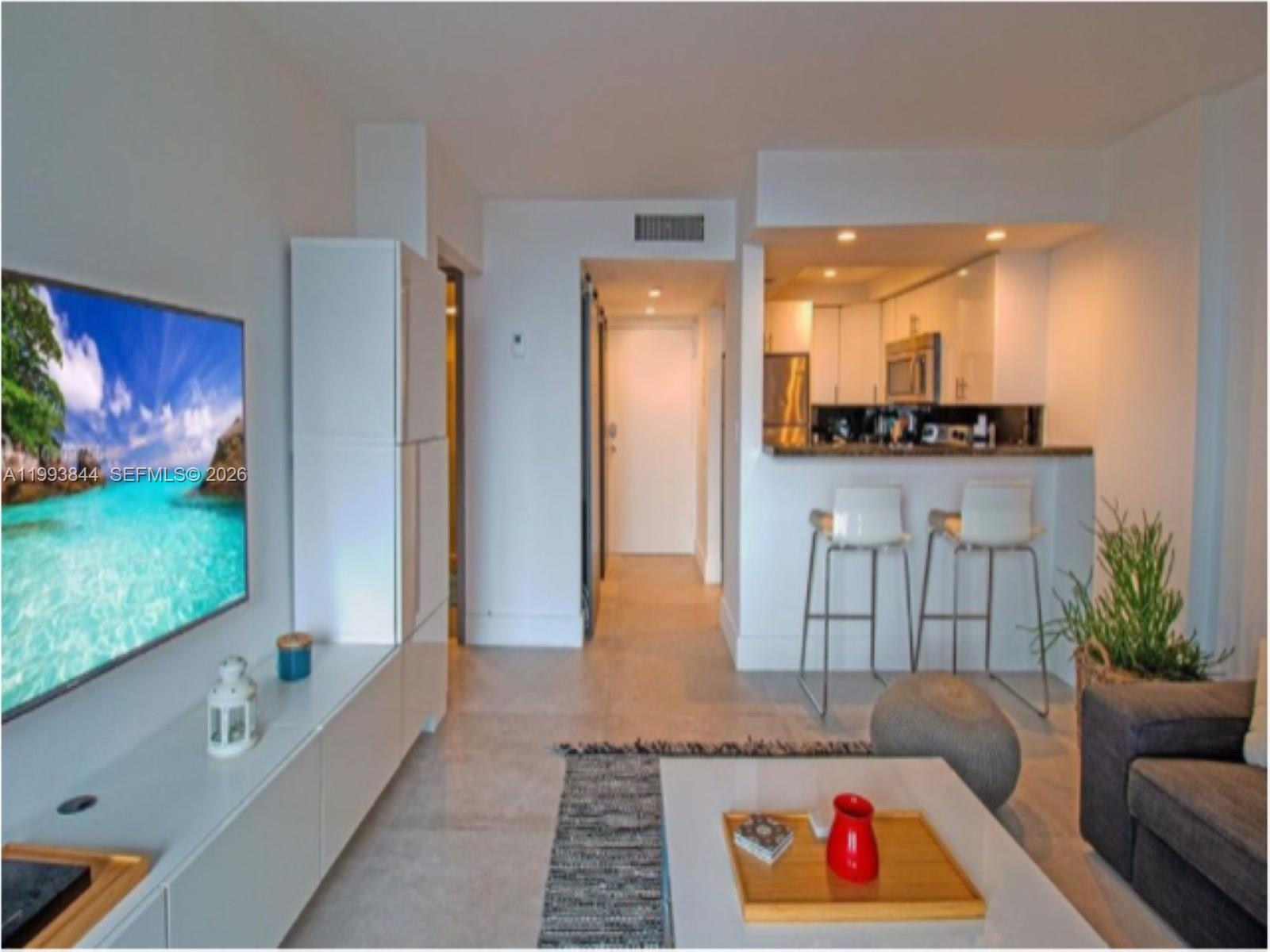 A living room with a white media console, kitchen breakfast bar, and light tile flooring — 1035 West Ave # 802, Miami Beach FL 33139, MIAMI BEACH, FL