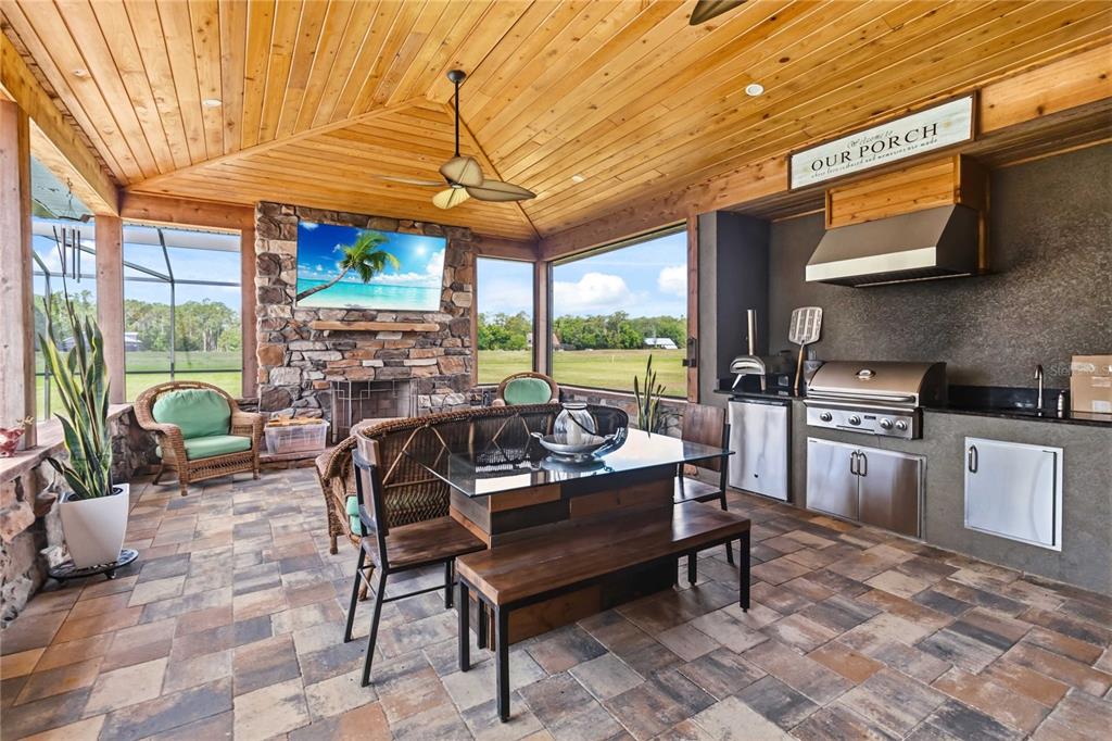 A covered outdoor patio features a stone fireplace, dining area, and a built-in kitchen — 4901 MANOR HOUSE LANE, ST CLOUD, FL